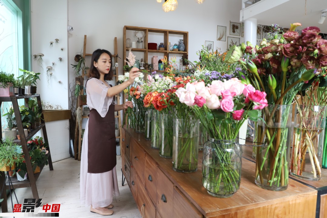 王黎媛是一名河南姑娘，在昆明念完大學后，就再也舍不下春城的藍天陽光、青山碧水，更舍不下這里的四時繁花，于是就干脆留了下來，成了一名媒體人。2017年的時候又毅然辭去工作，創(chuàng)業(yè)開起了花店，成了都市里的一名“花房姑娘”。圖為王黎媛在自己的花店中整理鮮花。新華網(wǎng) 周亞平/攝 念新洪/文